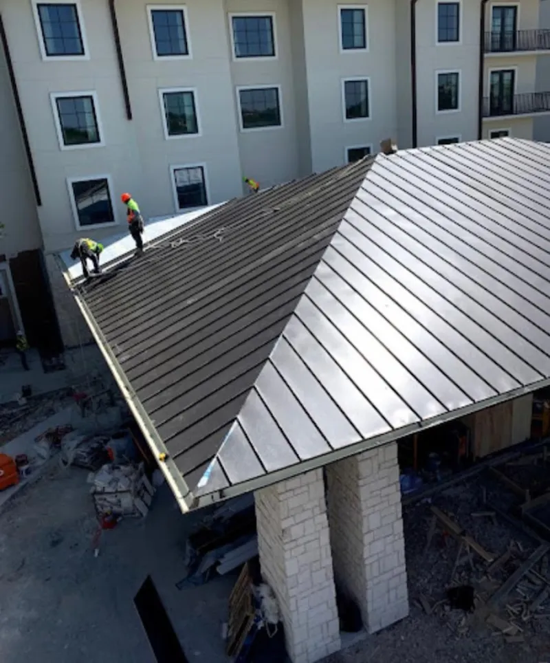 Crew installing standing seam metal roof panels on a commercial project in Tell City